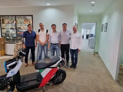 a group of men standing in a room with a scooter