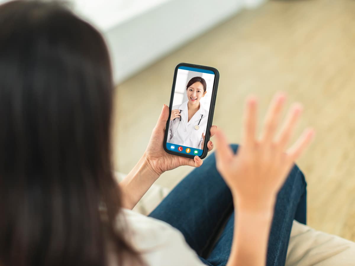 a woman holding a phone with a doctor on her screen