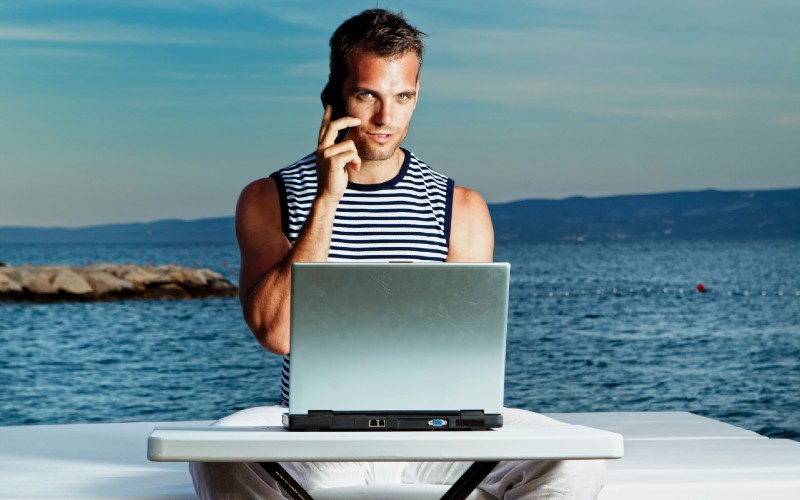 a man sitting at a table with a laptop and phone