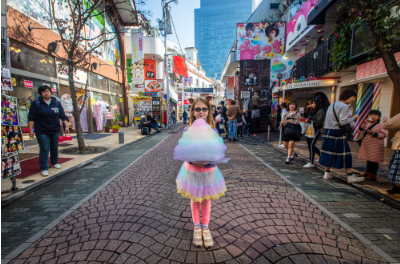 a girl holding a large cotton candy in a city