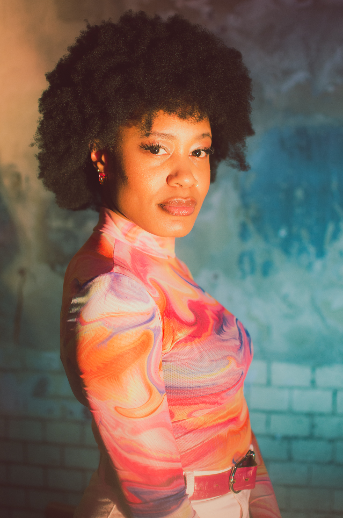 a woman with afro hair wearing a colorful shirt