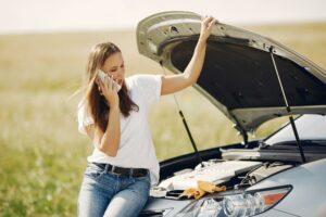 a woman sitting on a car with her hands up