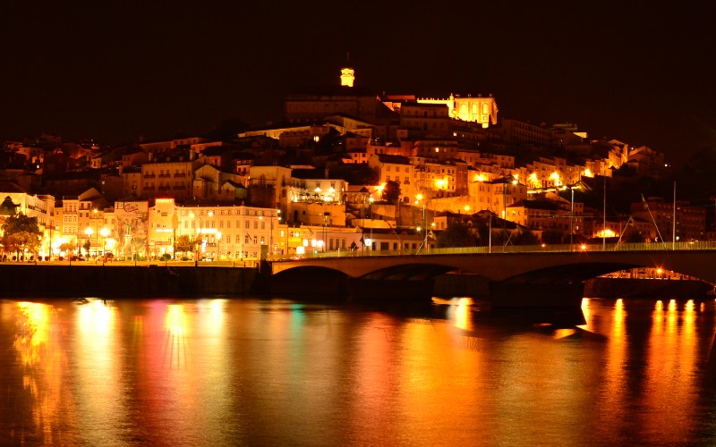 a city at night with lights on the top of a hill