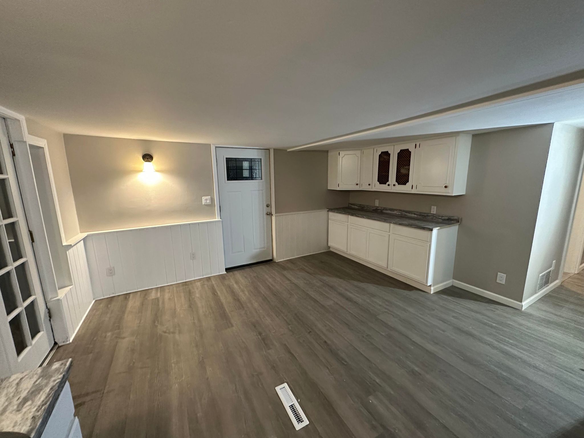 a room with white cabinets and wood floors