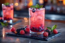 a glass of red drink with berries on a black tray