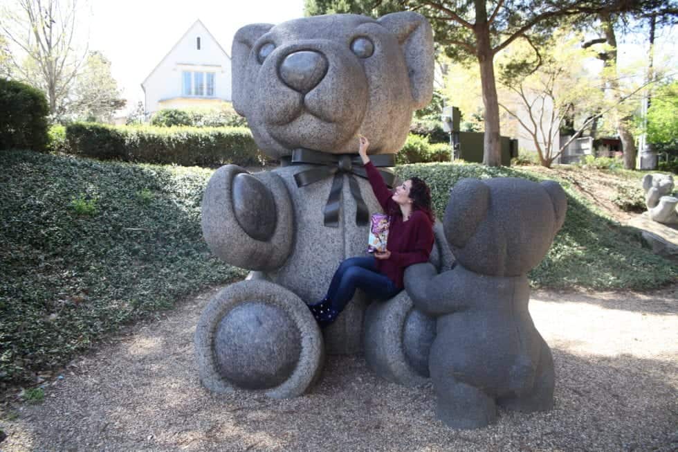 a woman sitting on a large stone bear statue