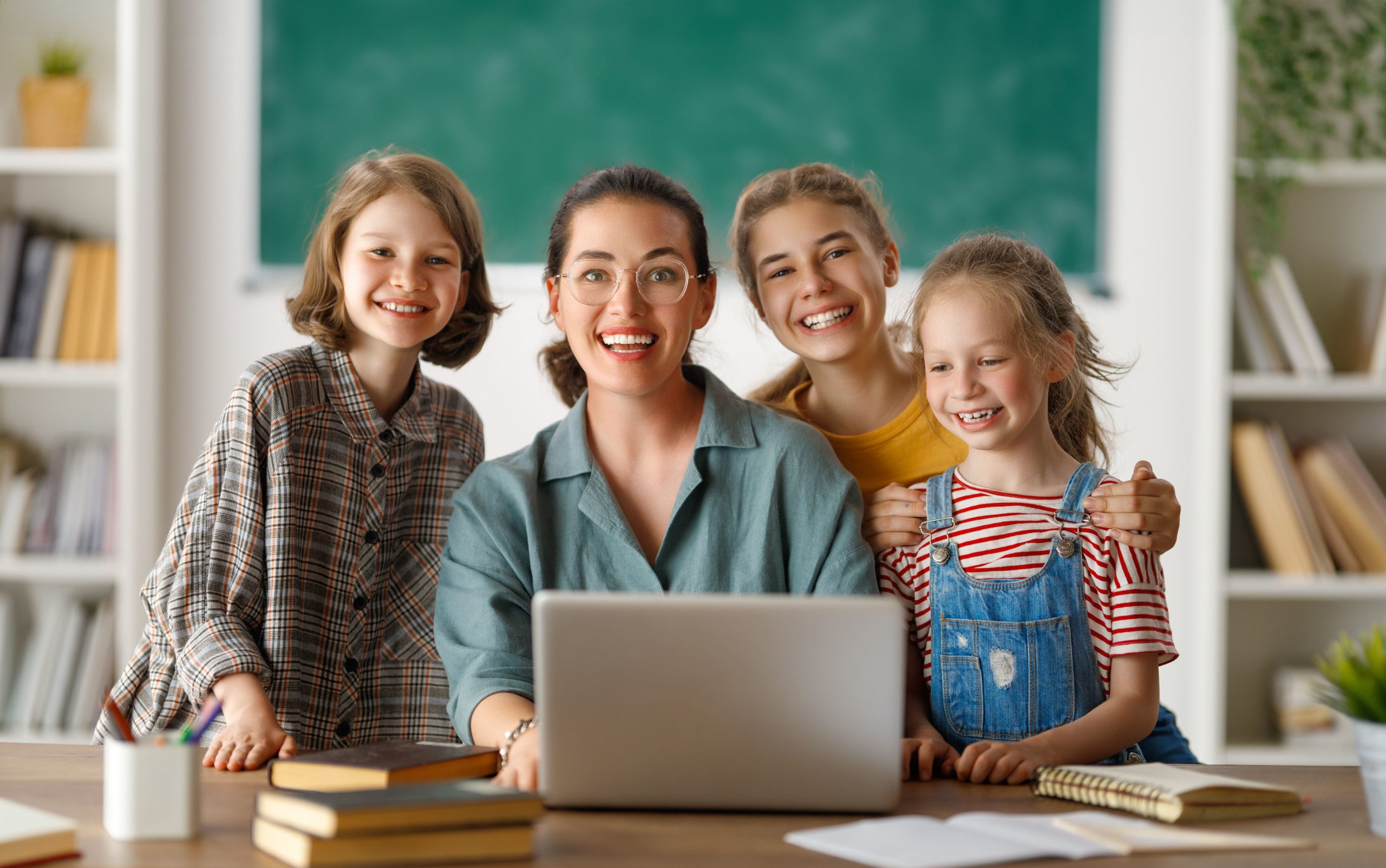 a woman and children smiling at a laptop