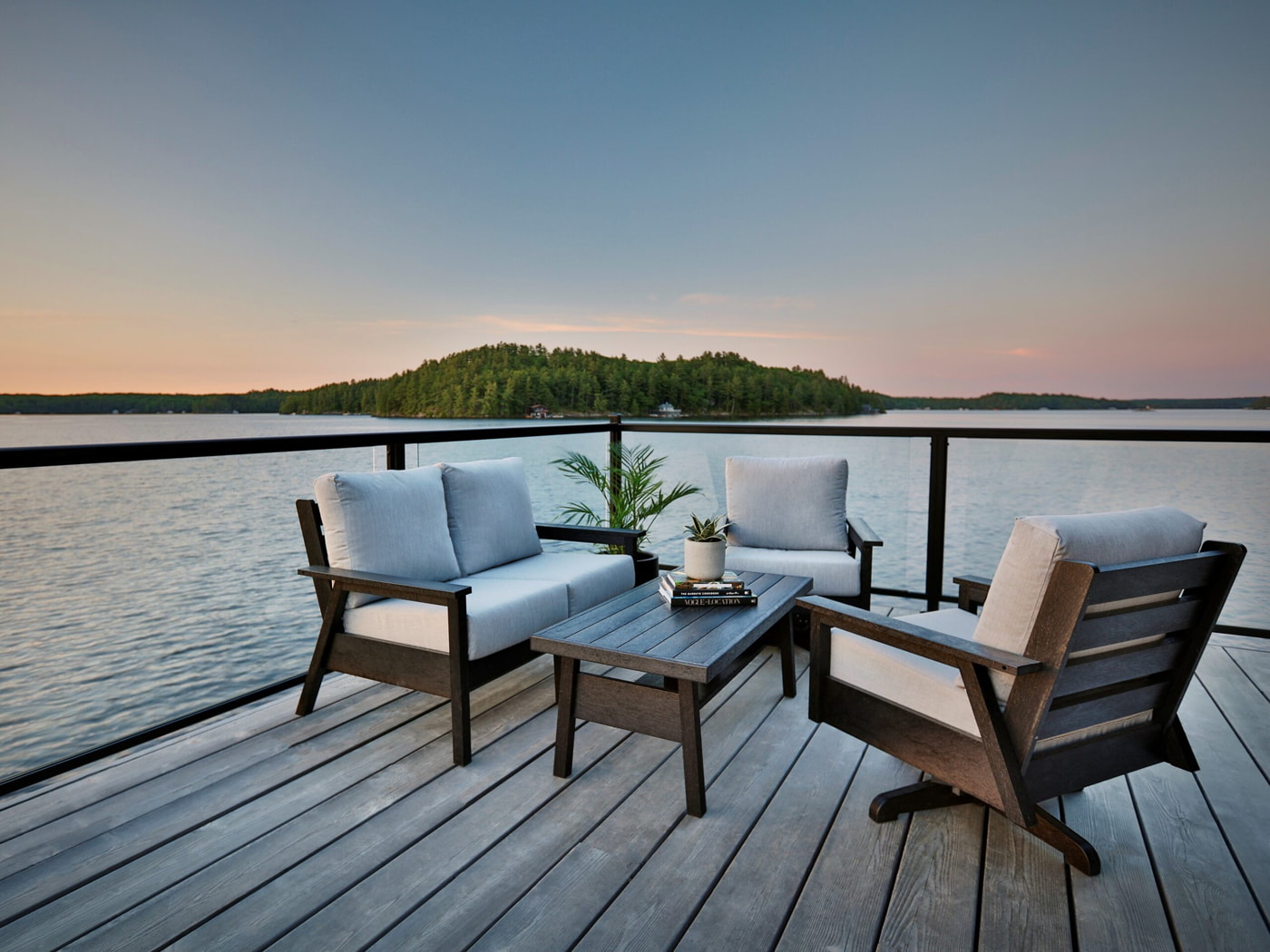 a deck with chairs and a table overlooking a body of water