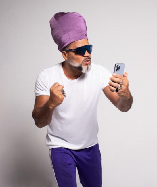 a man wearing purple hat and sunglasses holding up his fist