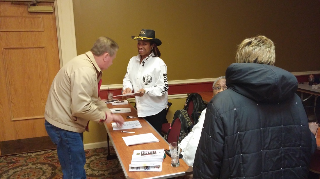 a man in a cowboy hat standing next to a table with people