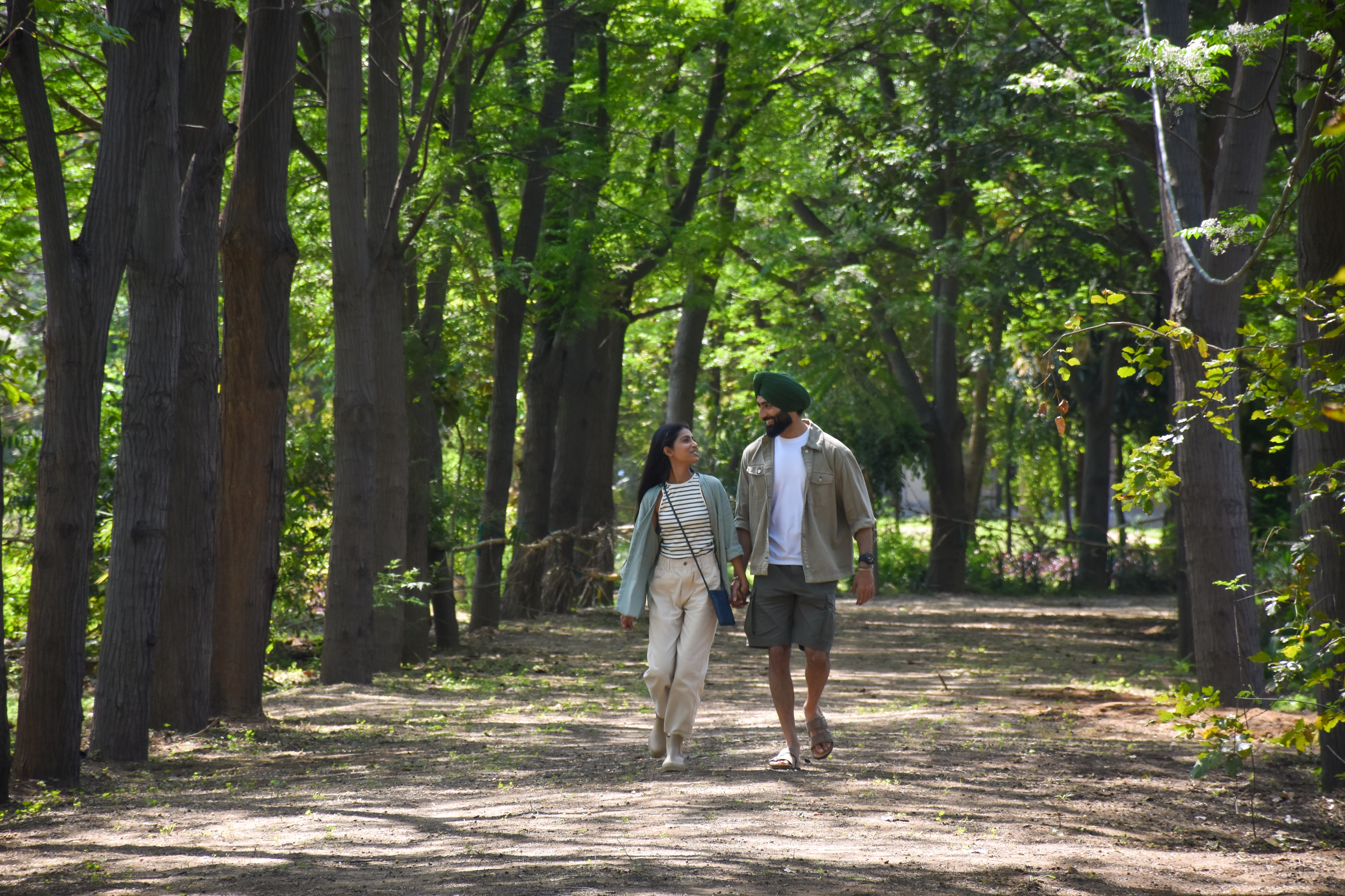 a man and woman walking on a path with trees