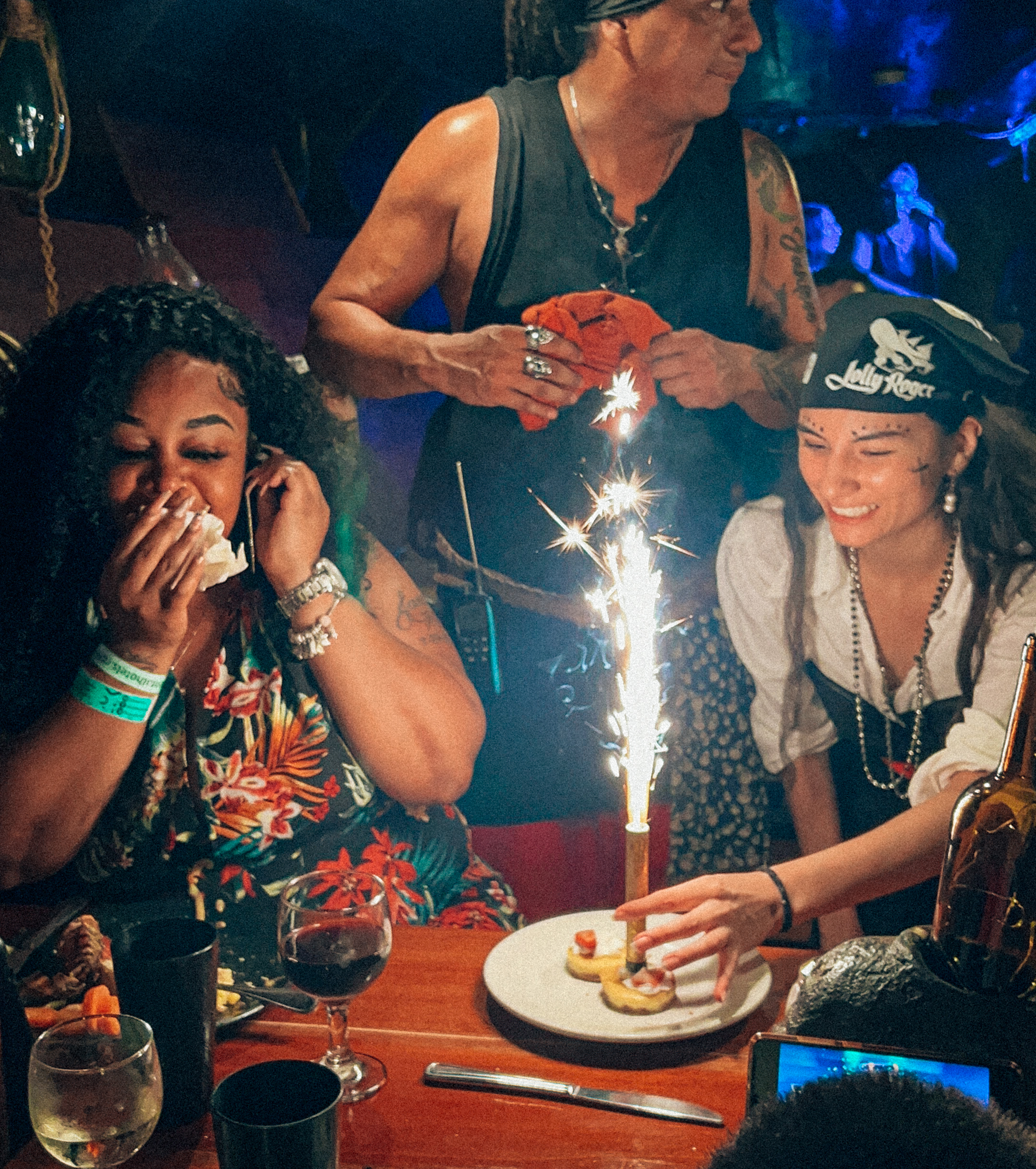 a group of people around a table with a cake and a candle