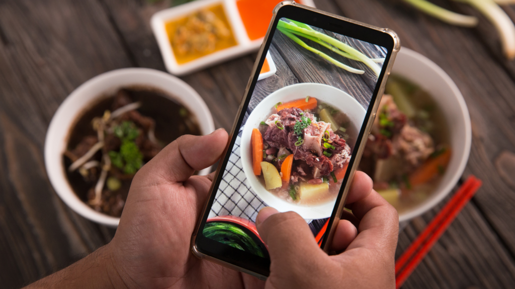 a person holding a phone with a bowl of food