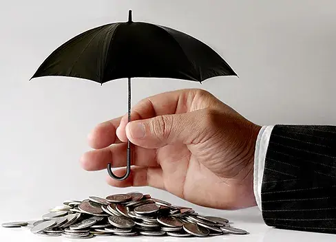 a hand holding an umbrella over coins