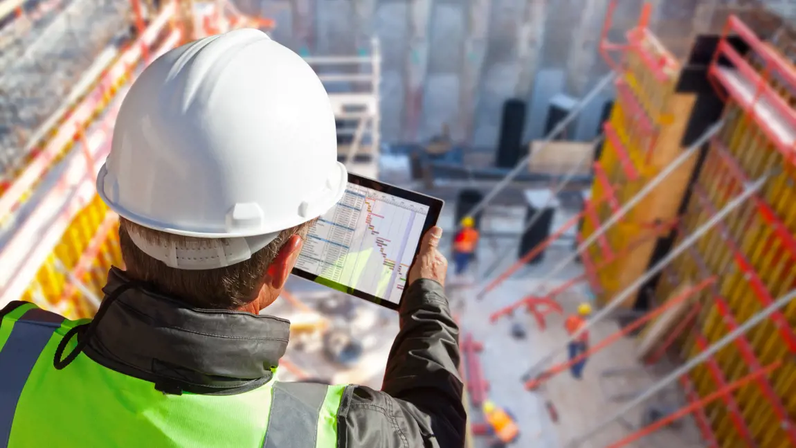 a man wearing a hard hat and holding a tablet
