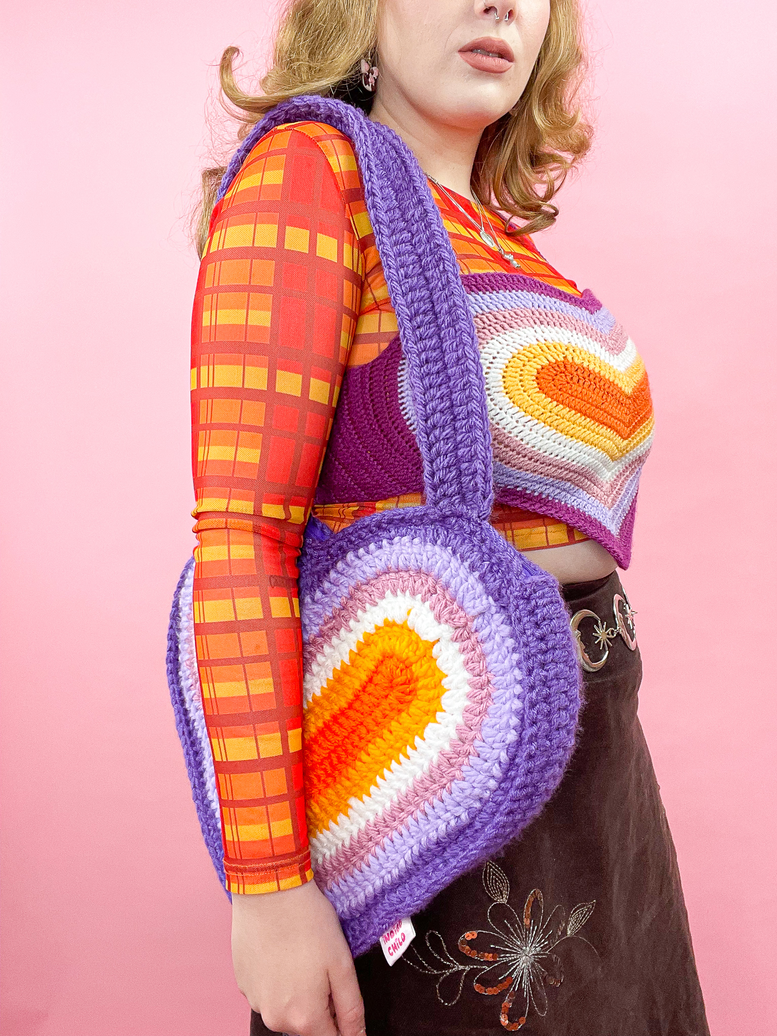 a woman wearing a colorful sweater and a knitted bag