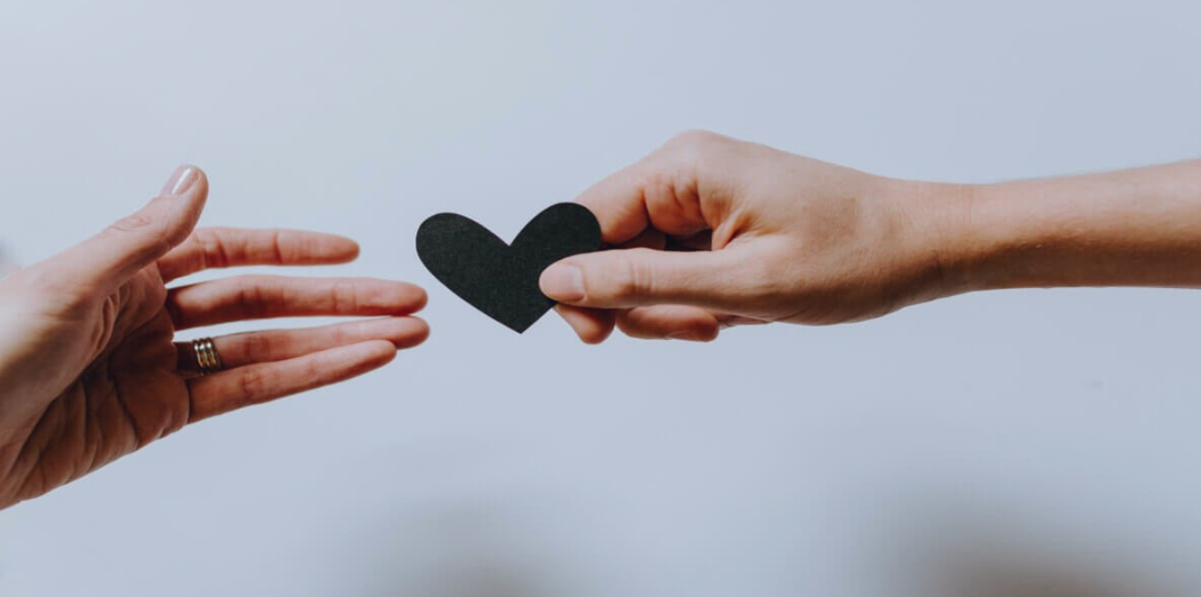 a hand holding a black heart