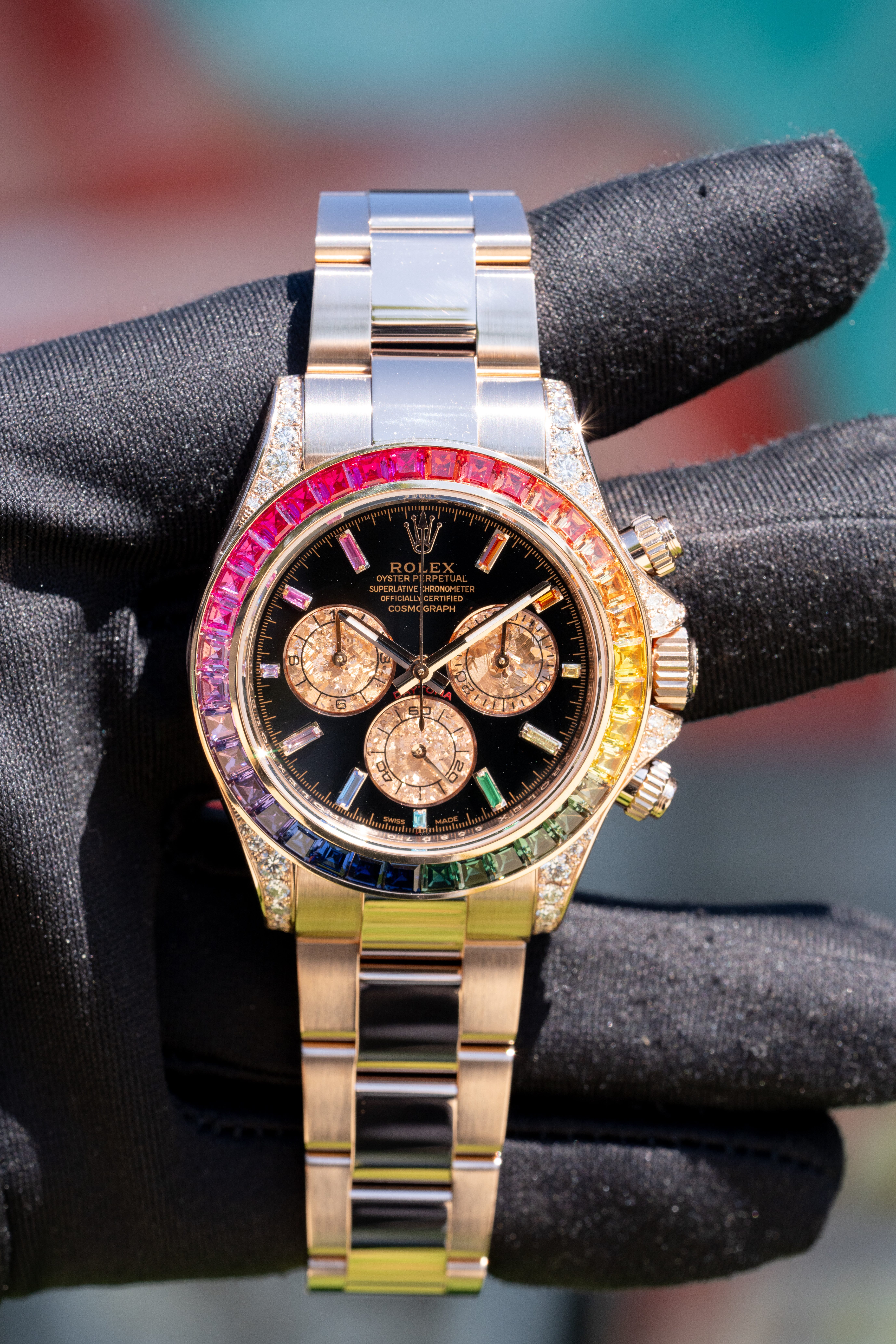 a watch with multicolored stones on a black glove