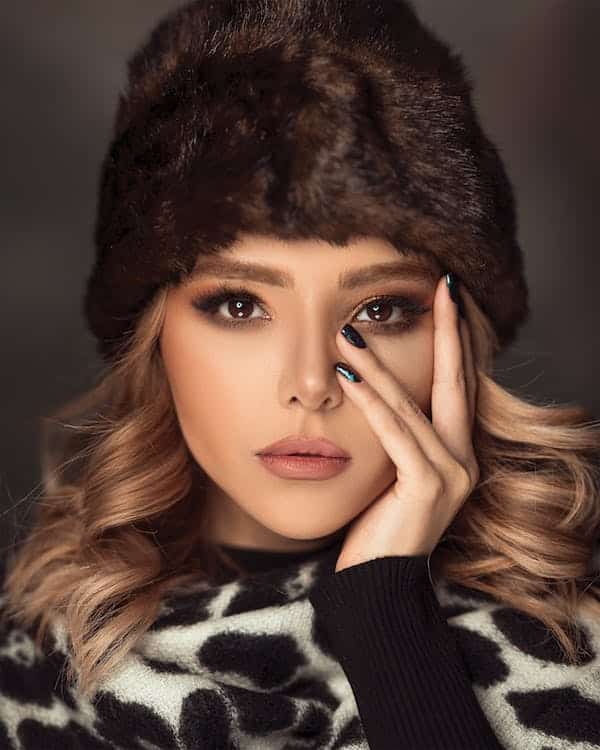 a woman with a fur hat and a hand on her face