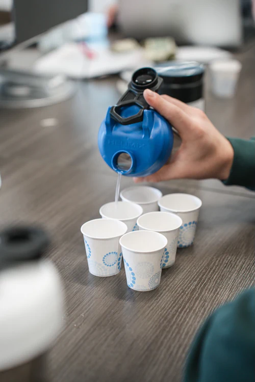 a person pouring liquid into cups