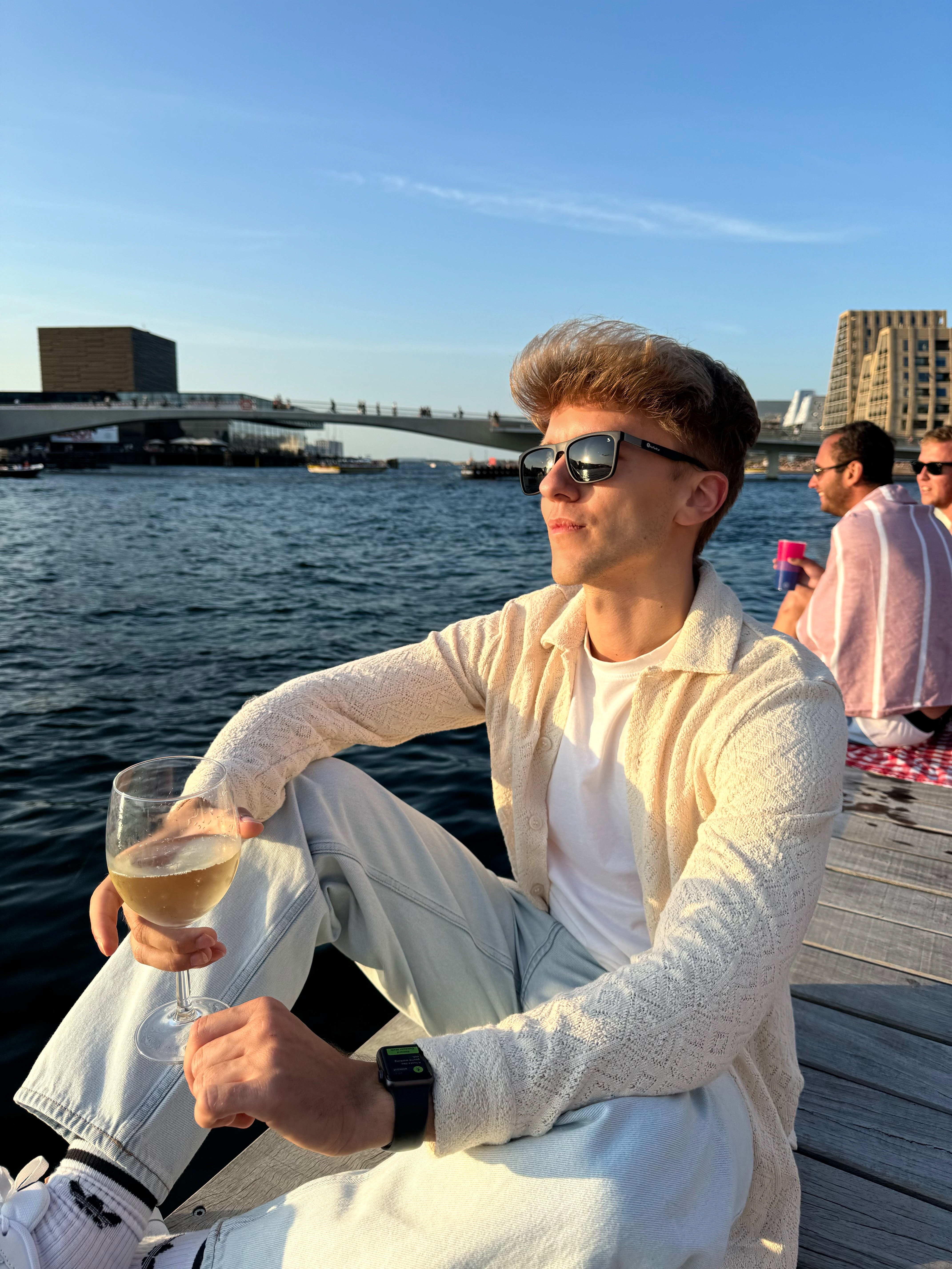 a man sitting on a dock holding a glass of wine