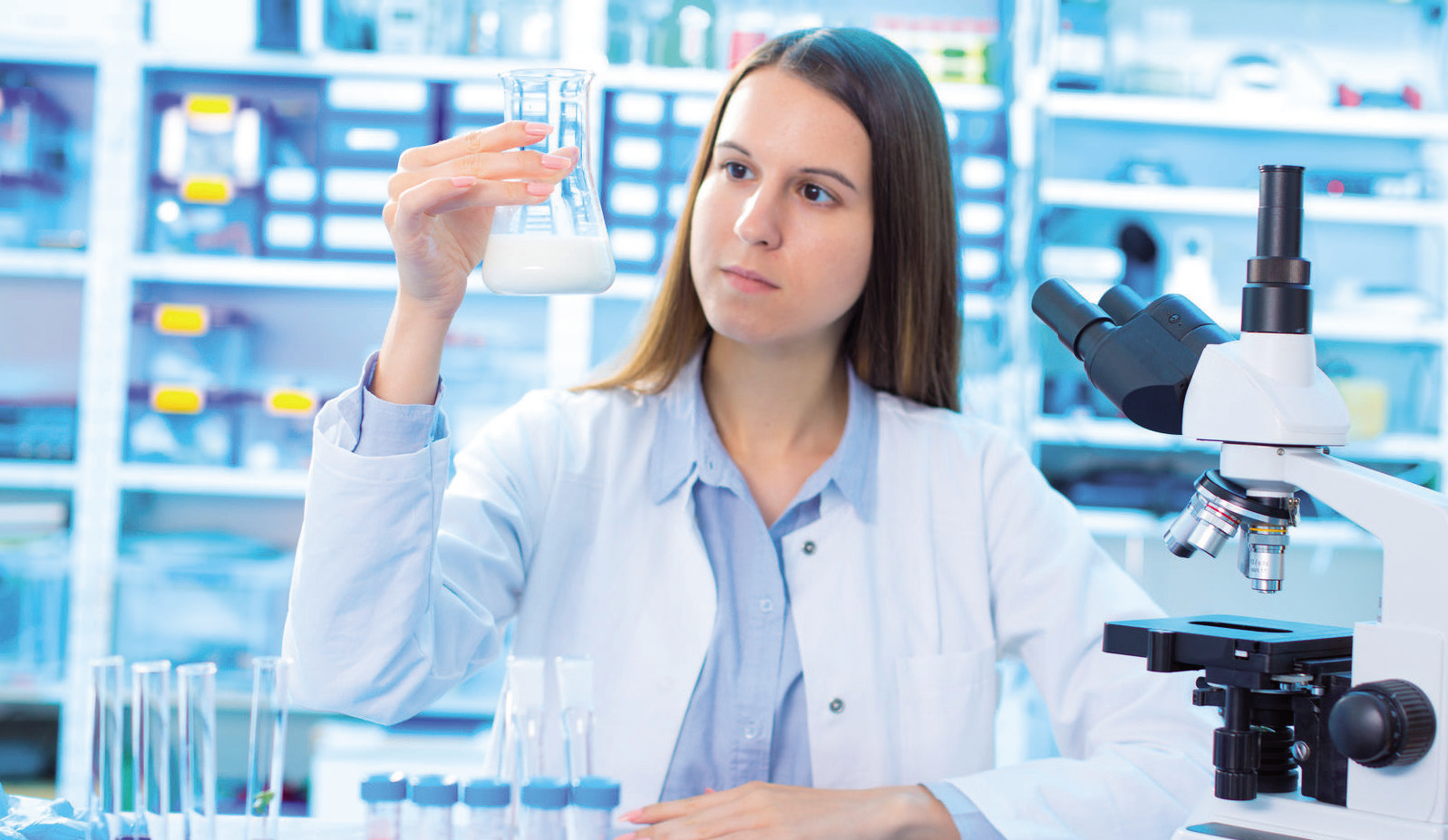 a woman holding a beaker with a white liquid in it