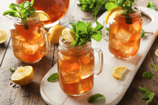 a group of glasses of iced tea with lemons and mint