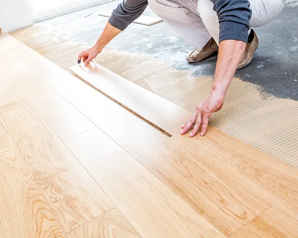a person using a wood plank to lay a floor