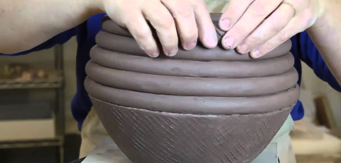 a person's hands on a clay bowl