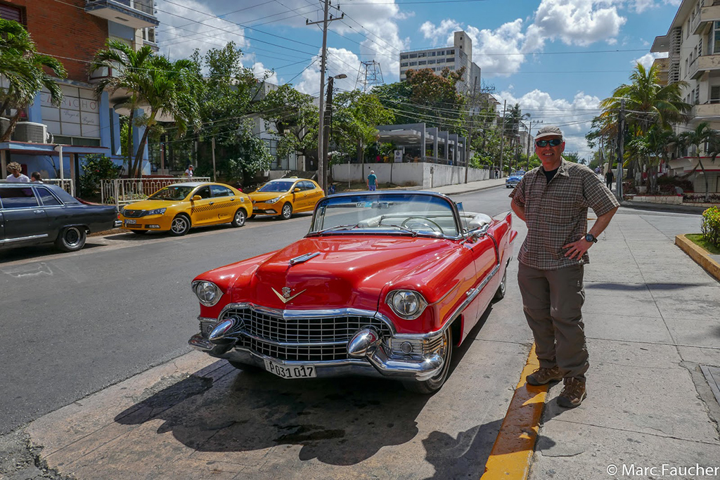 a man standing next to a red car