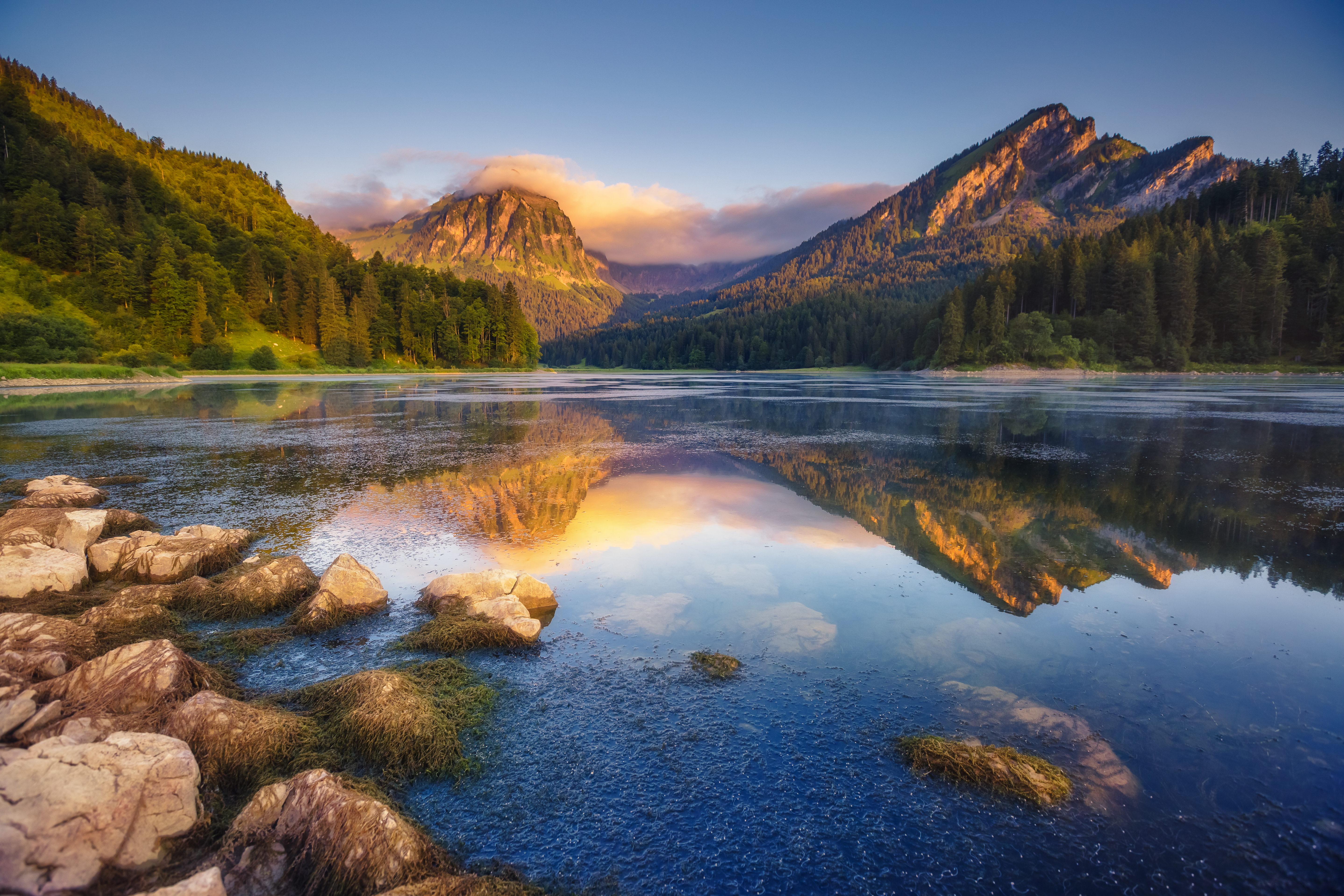 a lake with rocks and mountains in the background