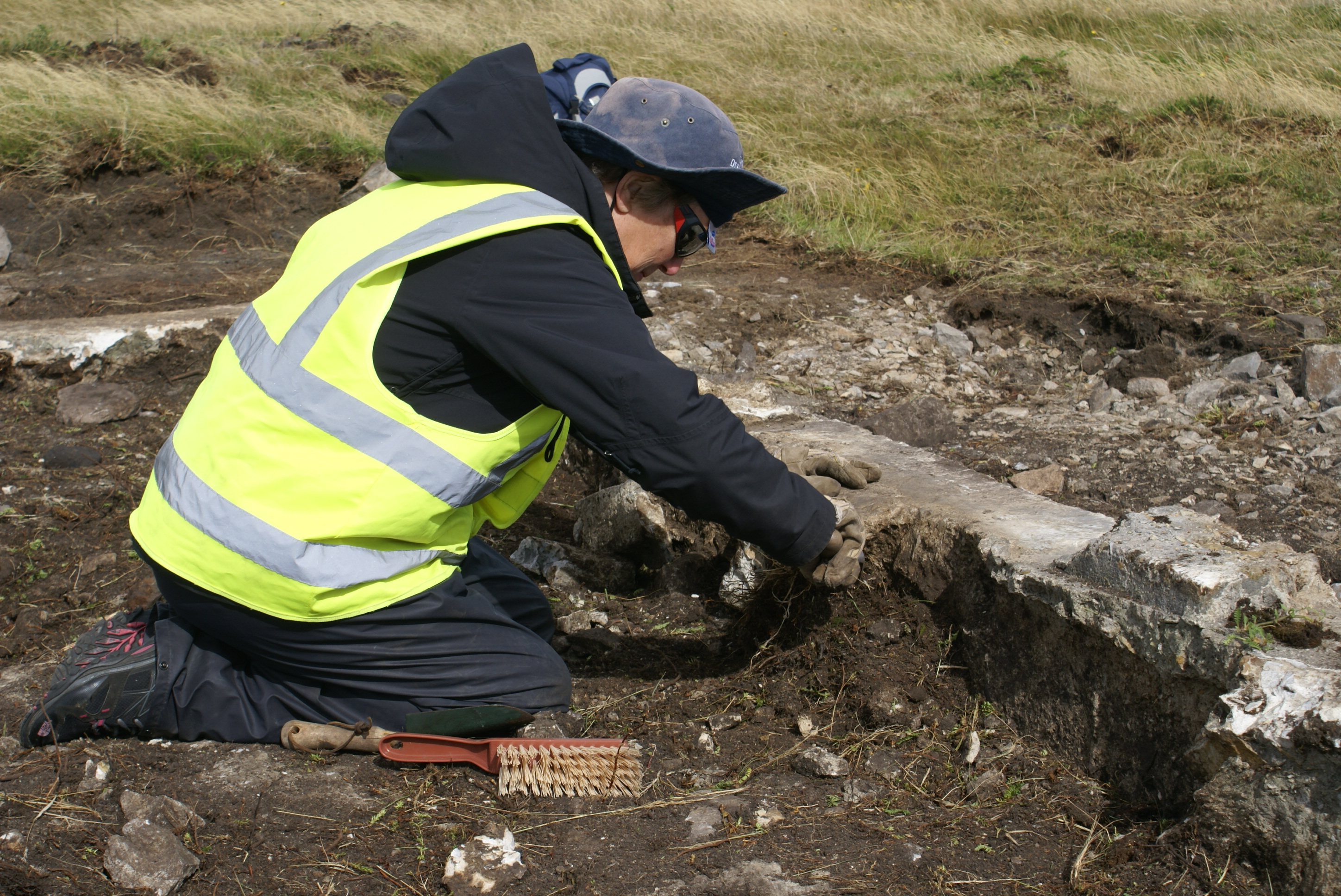 a man in a yellow vest digging a hole in the ground