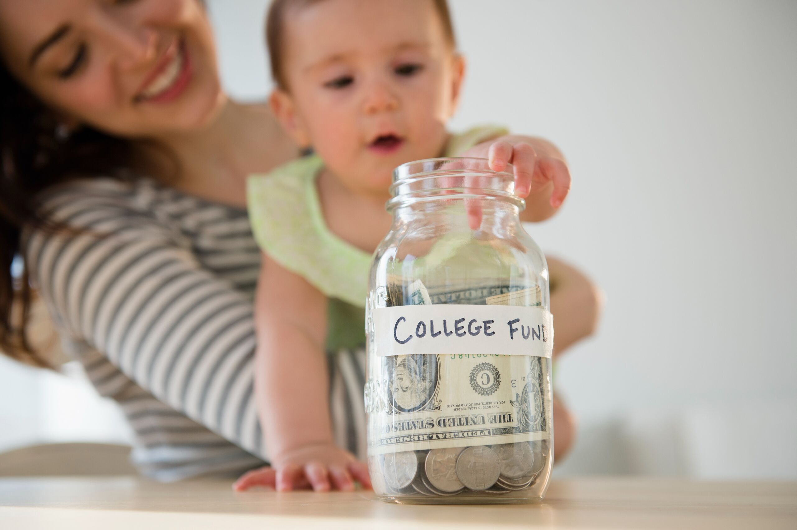 a woman and baby looking at a jar of money