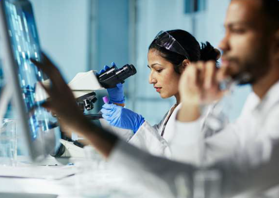 a group of people in lab coats looking through a microscope