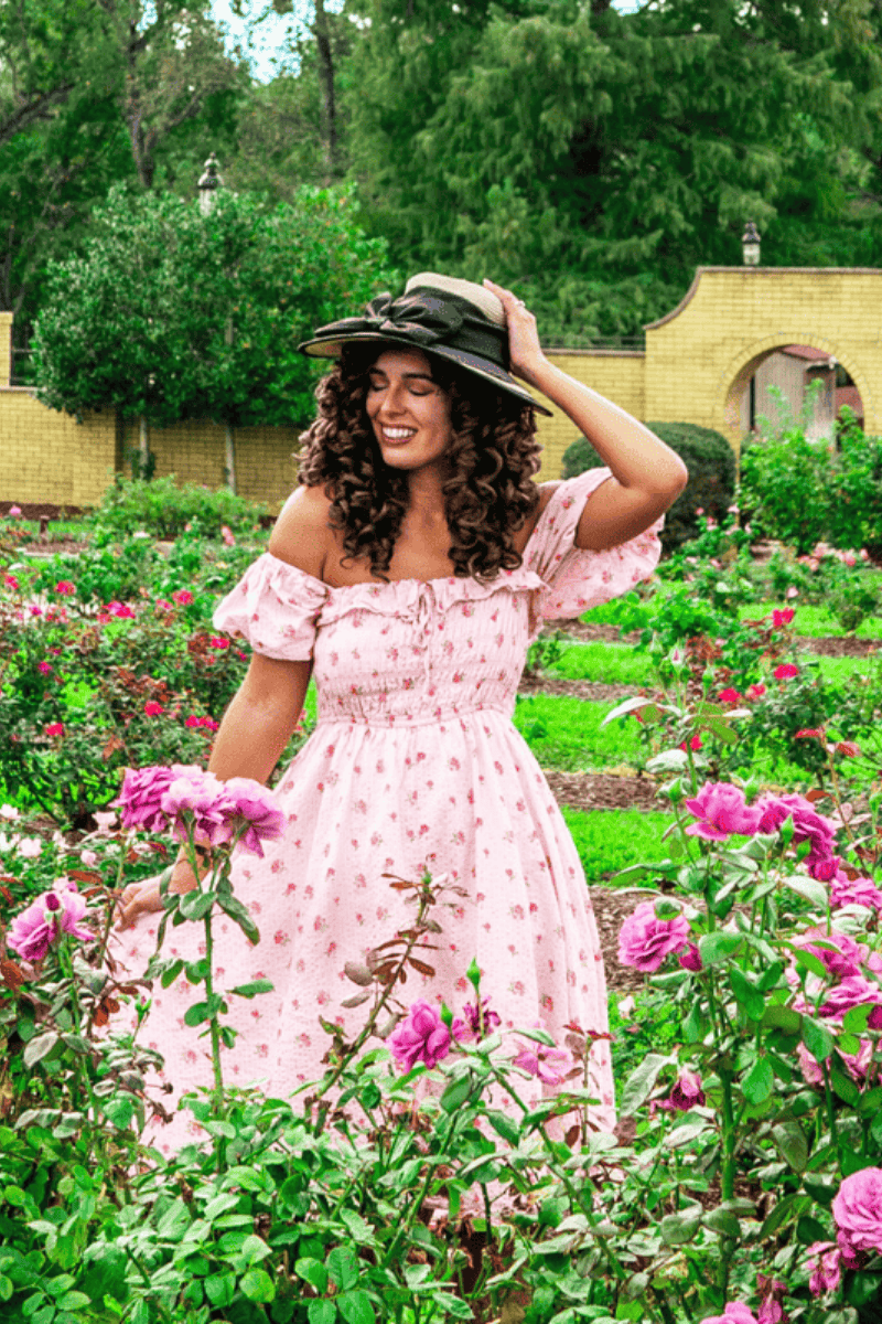 a woman in a pink dress in a garden with flowers