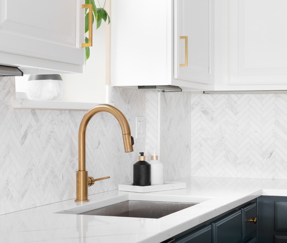 a white kitchen with a gold faucet
