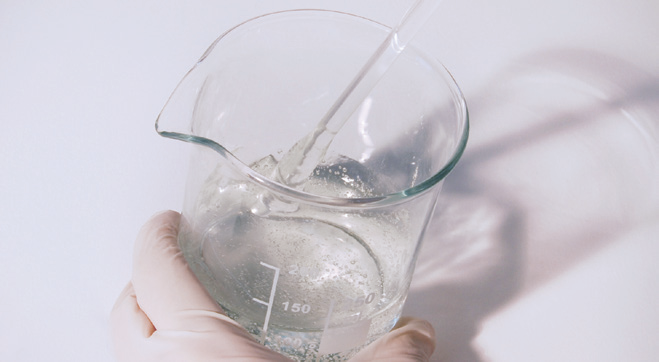 a hand holding a beaker with a pipette