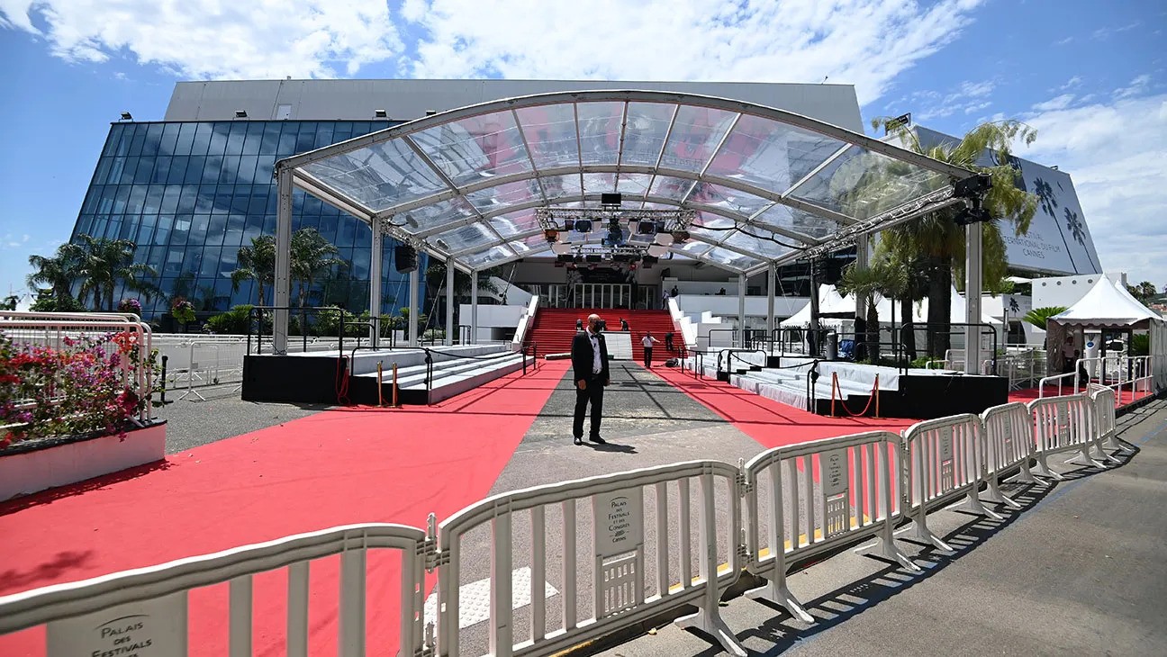a red carpet and a red carpet with a man standing in front of a building