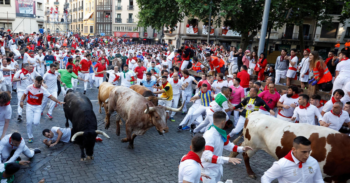a crowd of people running with bulls