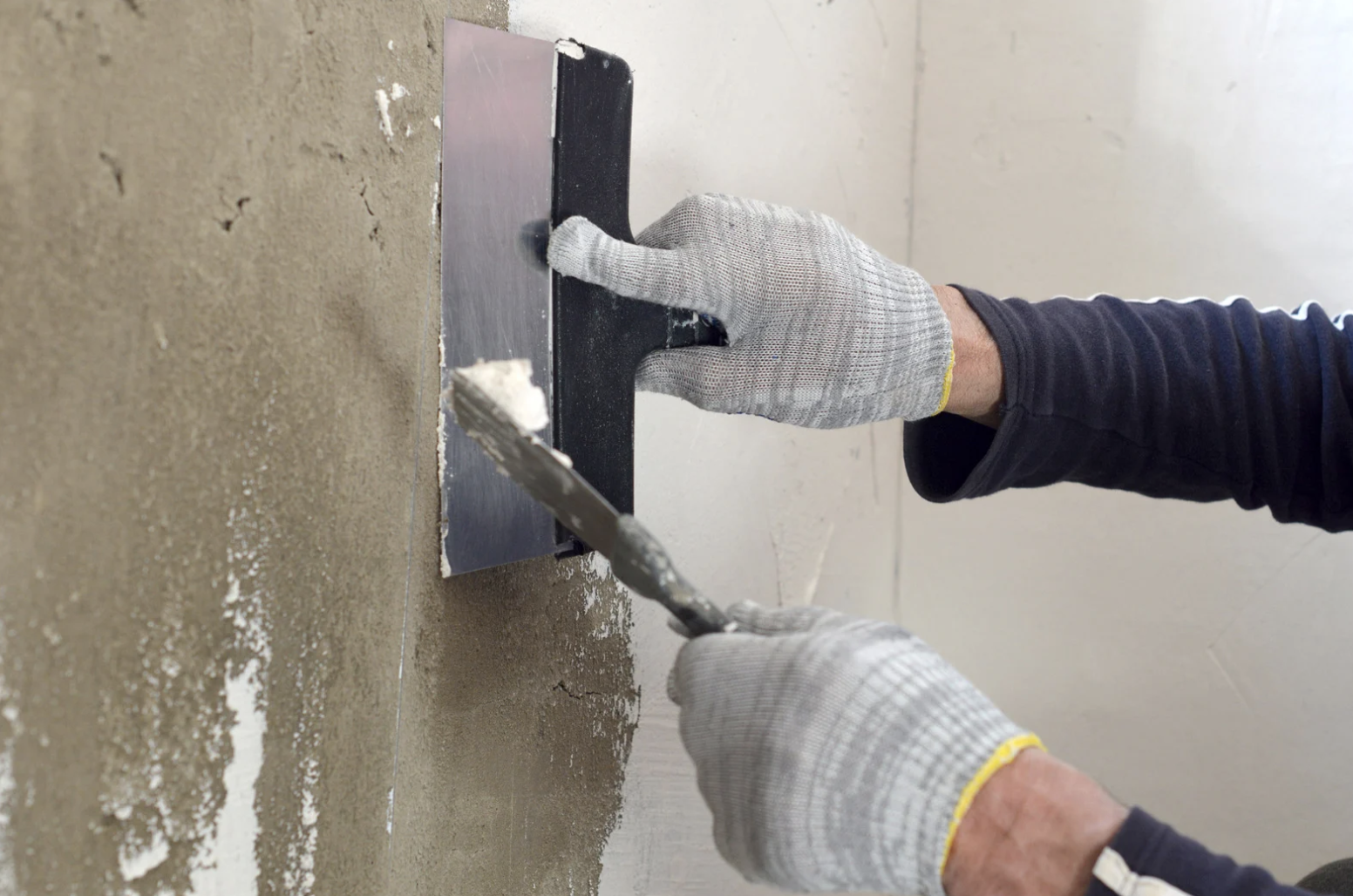 a person using a spatula to put plaster on a wall