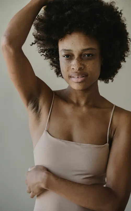 a woman with freckles holding her armpit