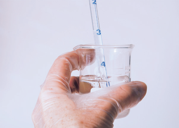 a hand holding a beaker with a straw