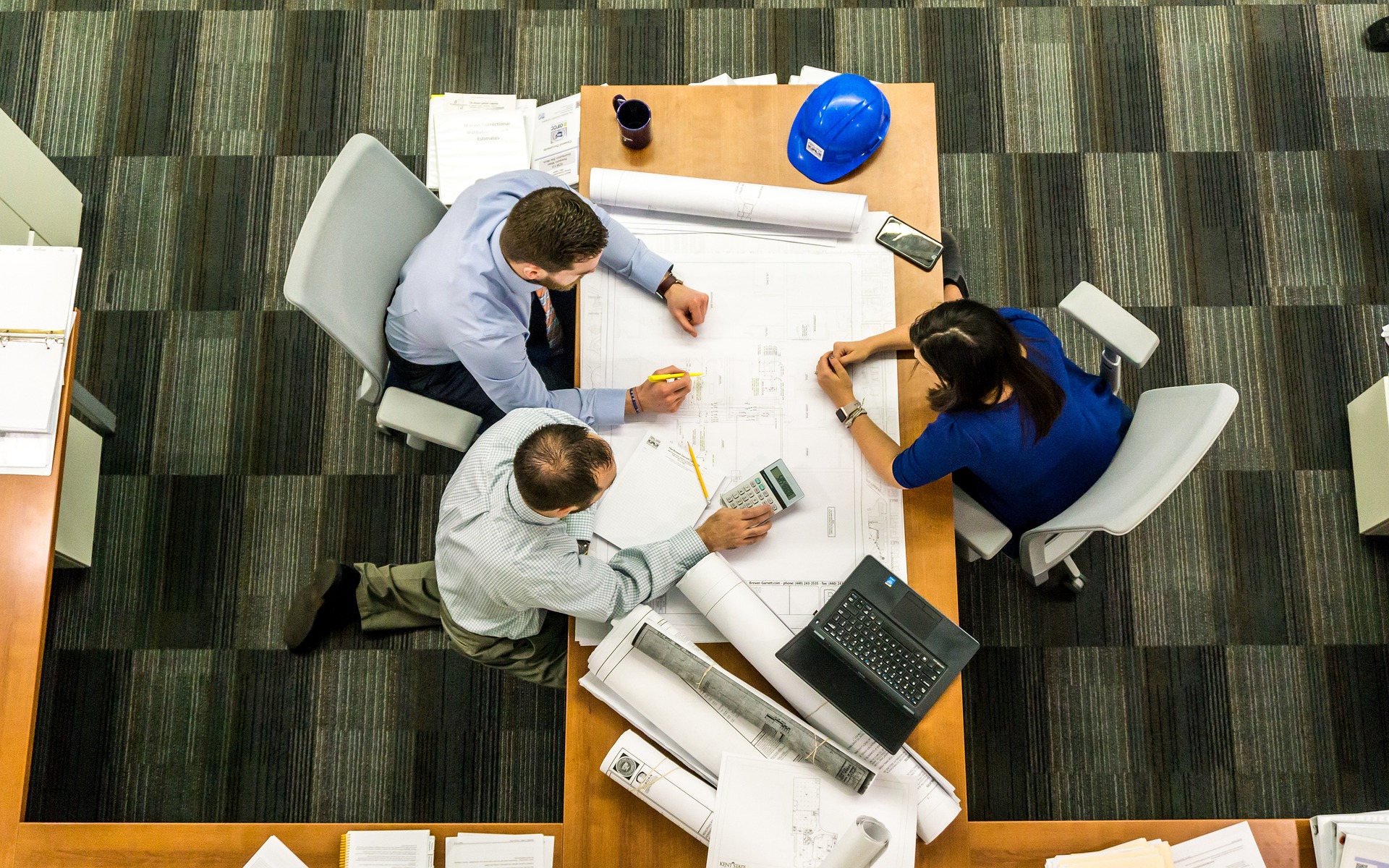 a group of people sitting around a table with blueprints