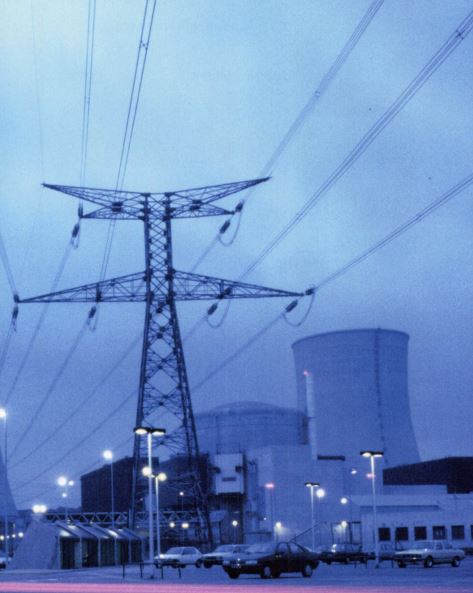 a power line tower in front of a nuclear power plant