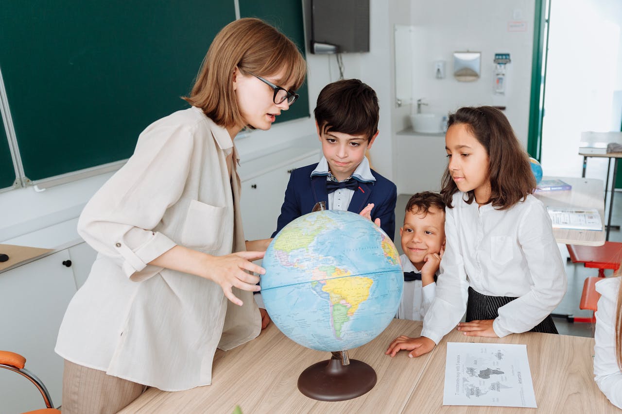 a woman and children looking at a globe