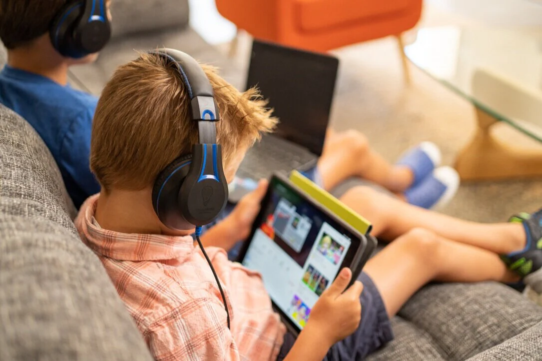 a boy wearing headphones and using a tablet