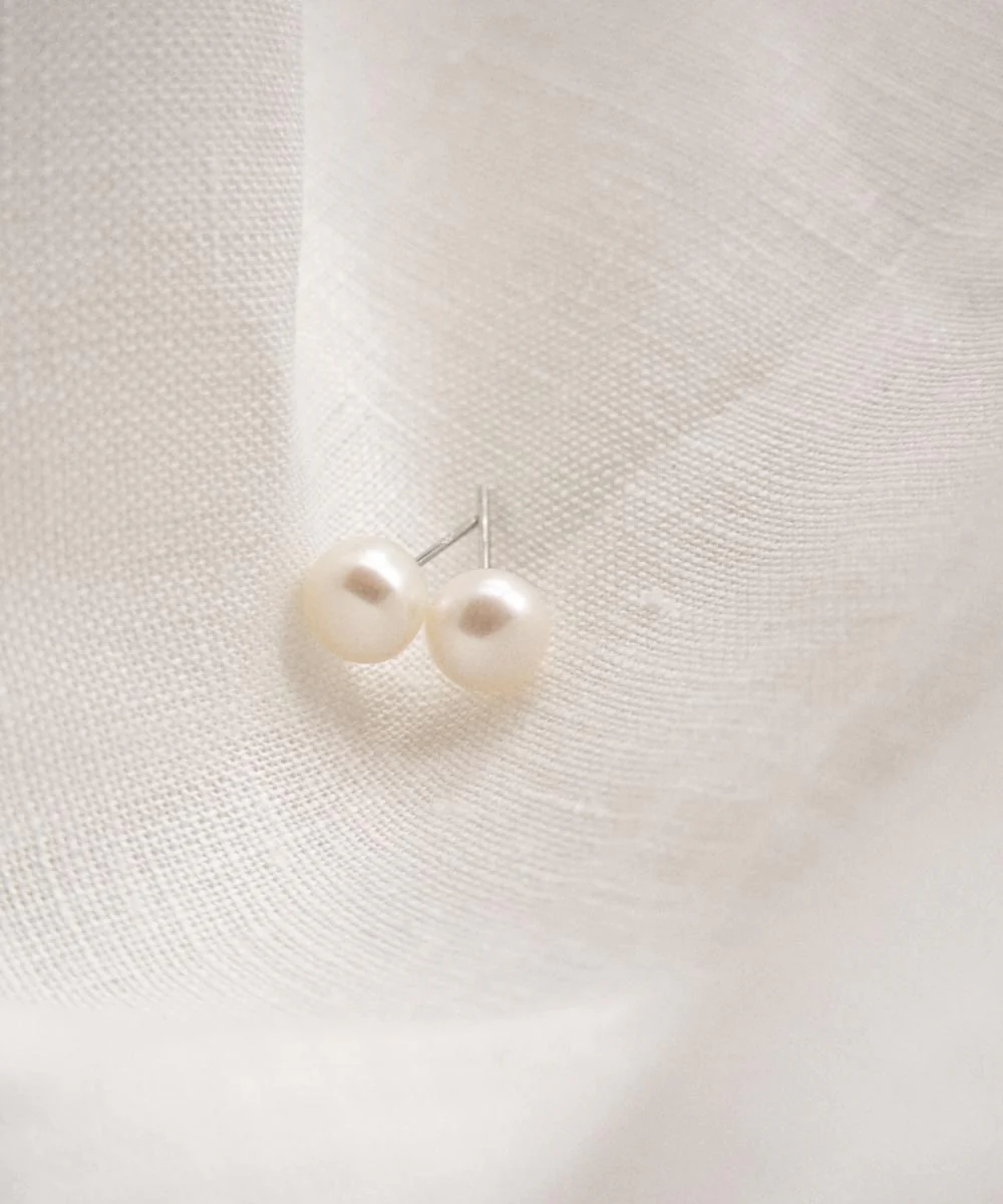 a pair of pearl earrings on a white fabric
