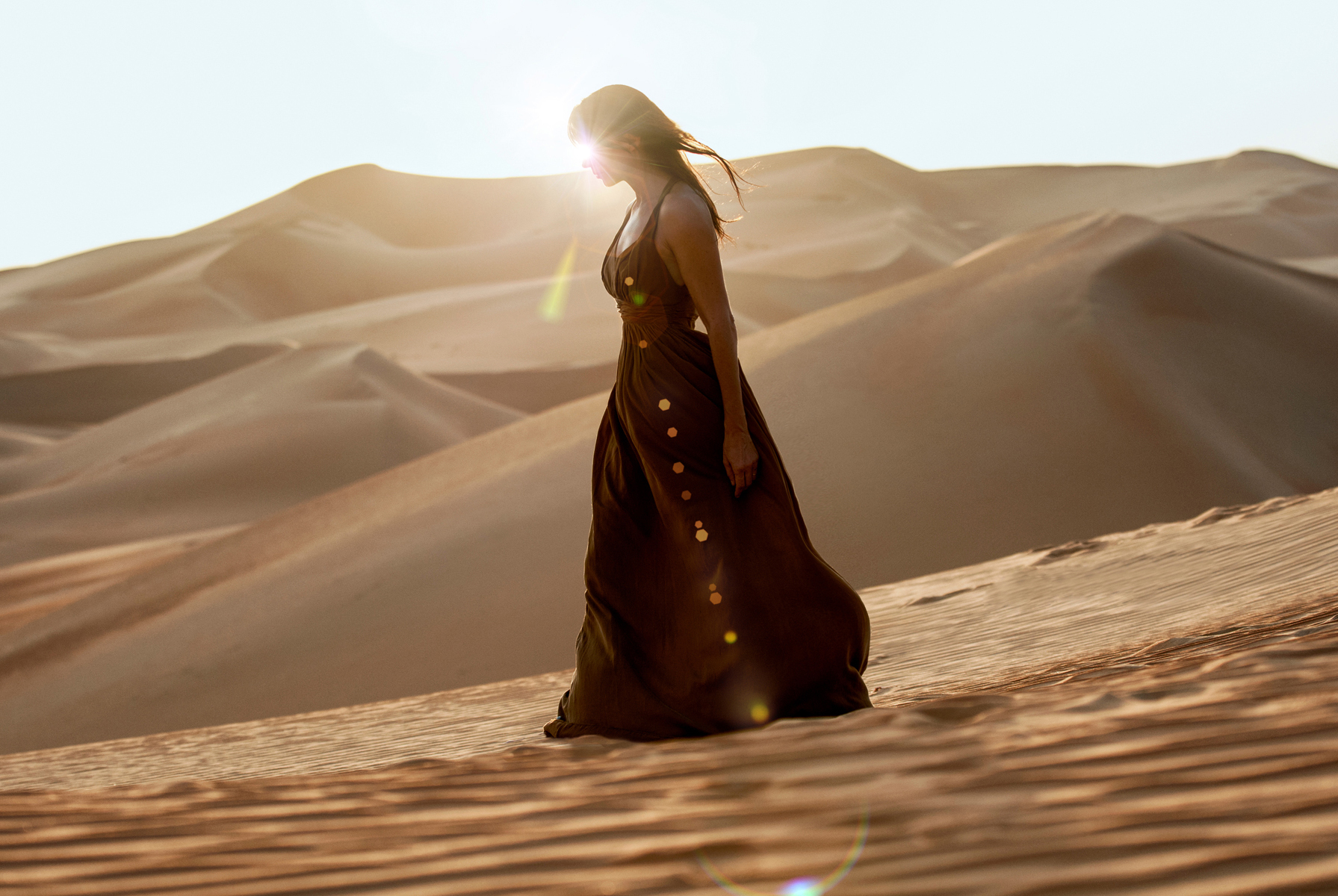 a woman in a dress walking in the desert