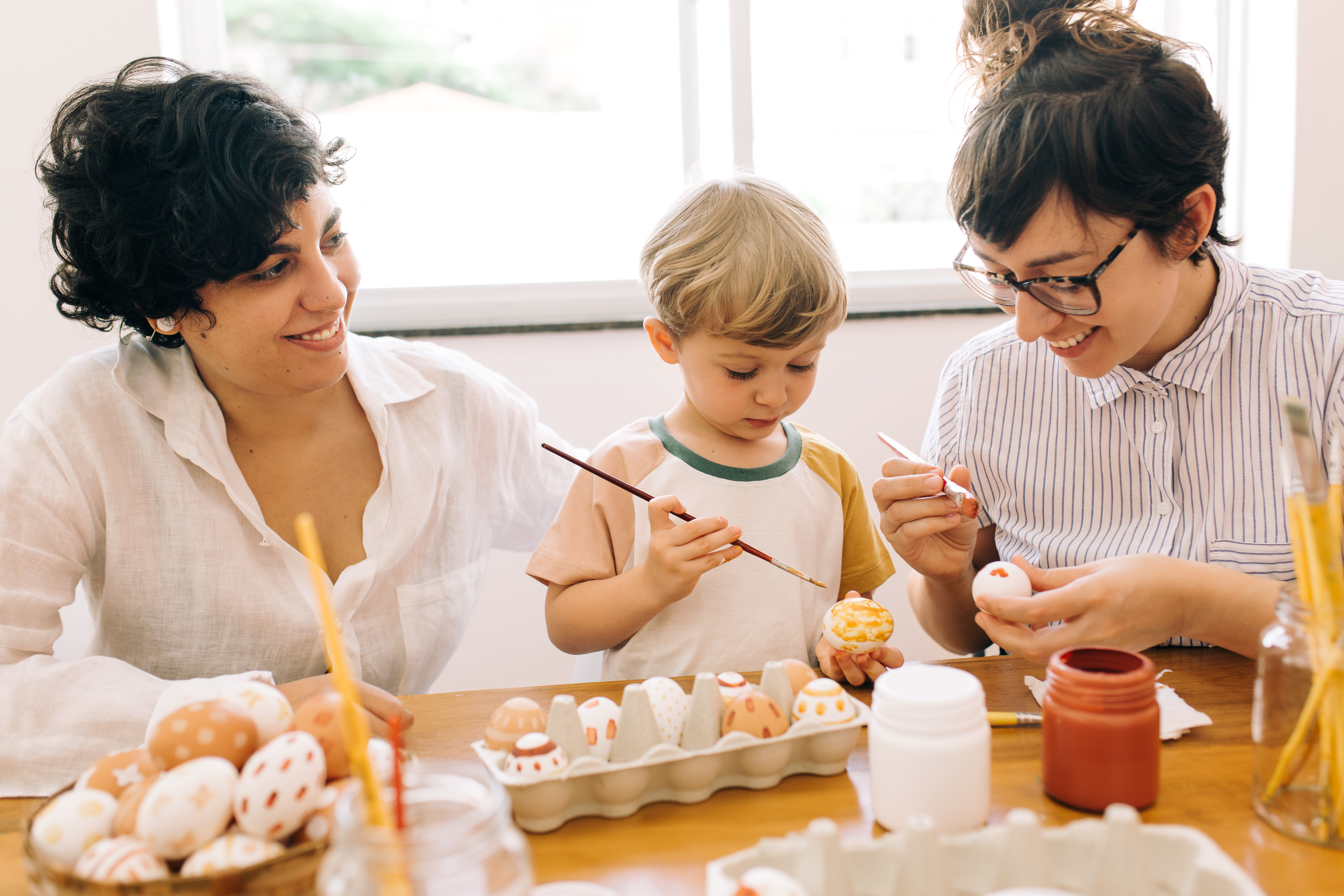 a woman and a child painting eggs