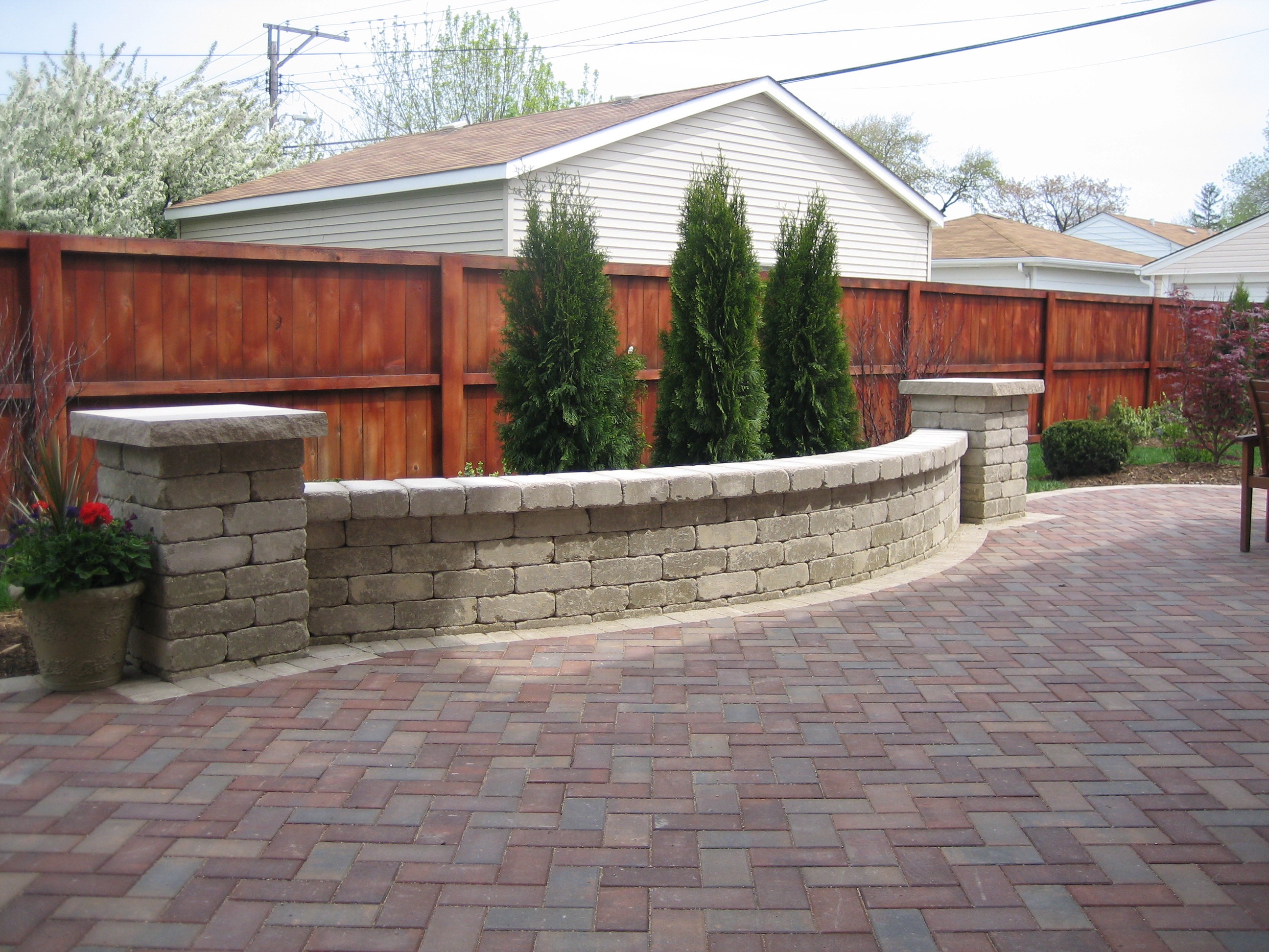 a brick patio with a fence and trees